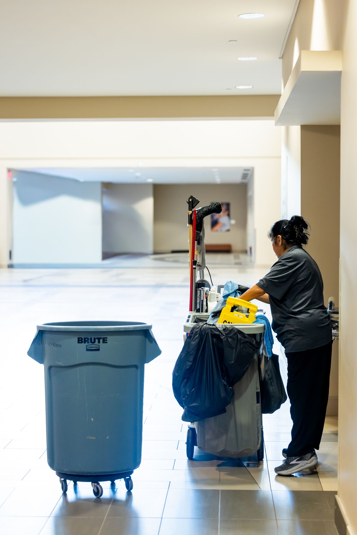 Janitorial staff with cleaning cart maintaining a commercial facility hallway